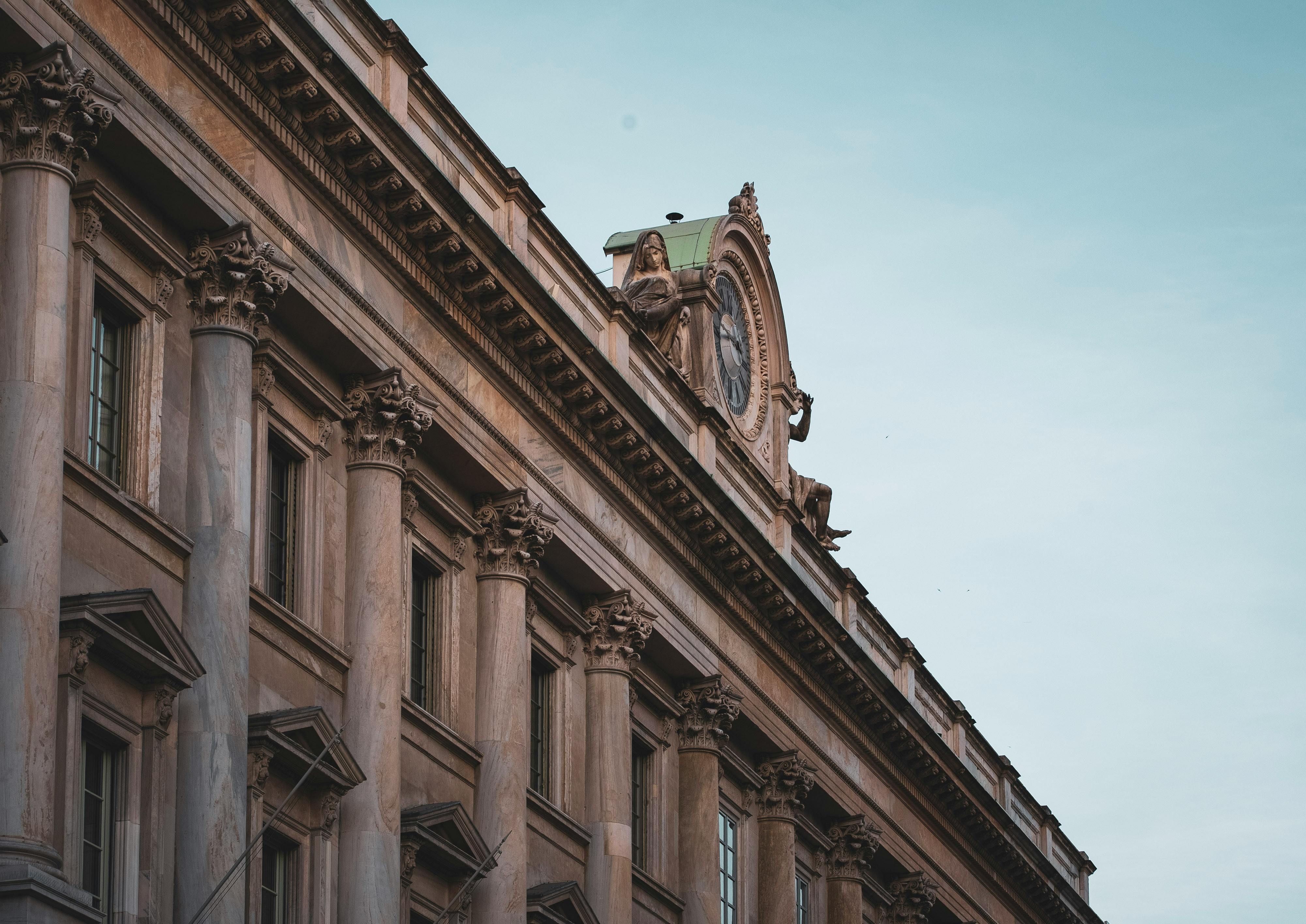 Neoclassical façade with Corinthian columns and a clock framed by sculpted figures