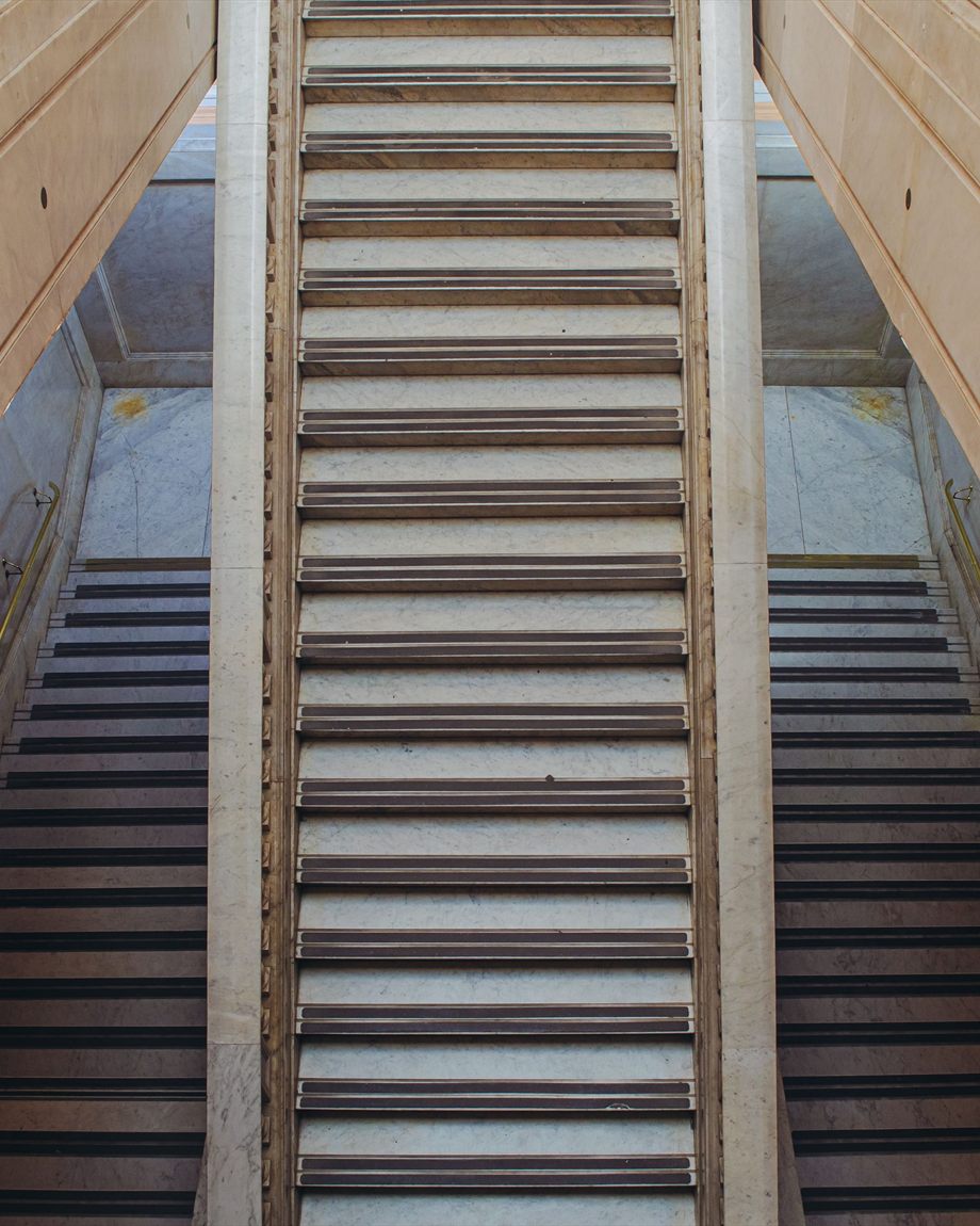 Symmetrical marble staircase rising through a classical interior